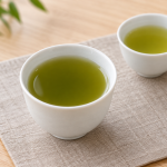 濃淡の異なる緑色の棒茶を入れた二つの白い湯のみ