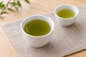 濃淡の異なる緑色の棒茶を入れた二つの白い湯のみ