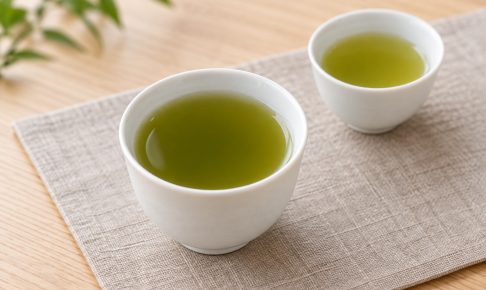 濃淡の異なる緑色の棒茶を入れた二つの白い湯のみ